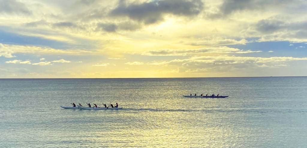 Two rowboats crossing each other as they head in opposite directions in the beautiful sunset.